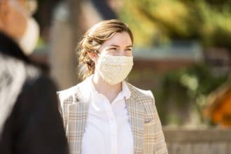 A woman wearing a mask gathers with a group of people at church