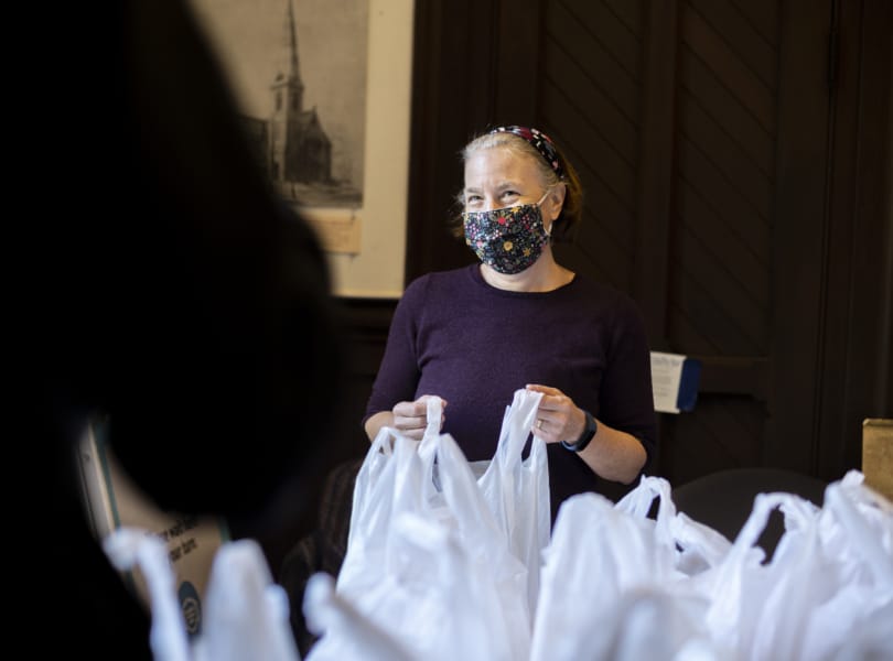 A woman hands a meal to a hungry person
