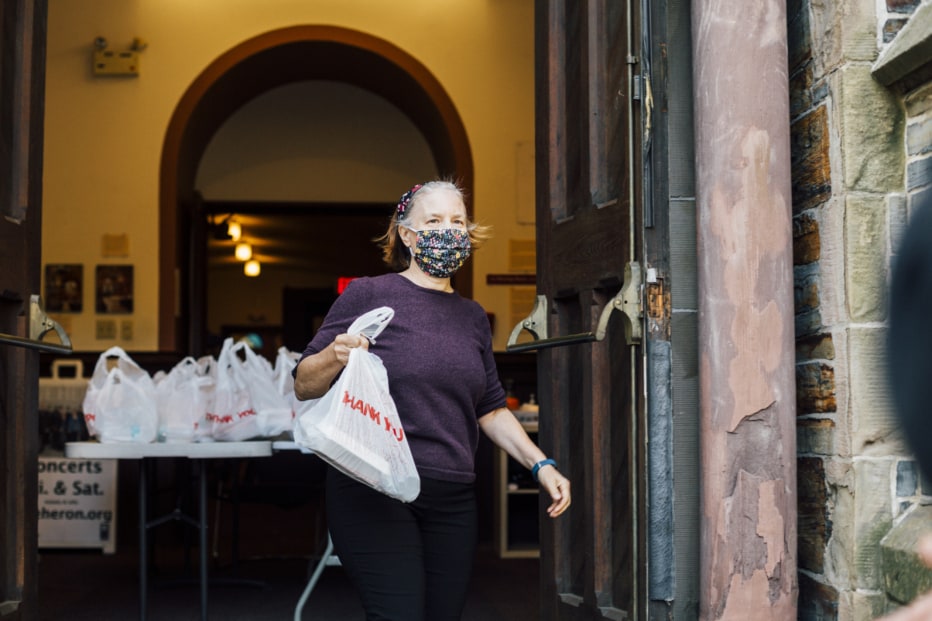 A woman carries a bagged meal for hungry people