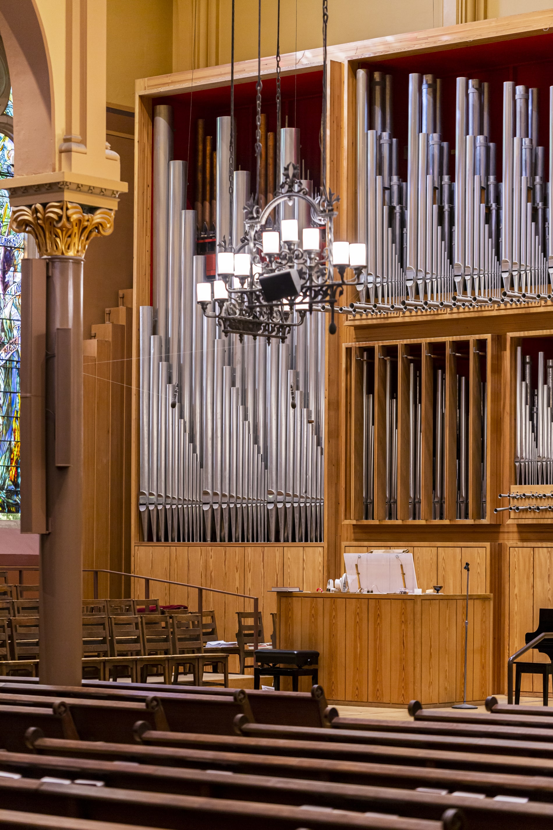 Organ pipes in the Sanctuary of First Church in Cambridge. A wrought iron chandelier hangs in the foreground.