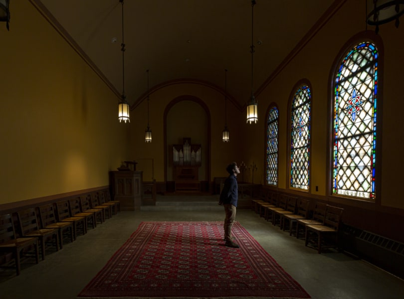 person standing in a chapel alone in darkness