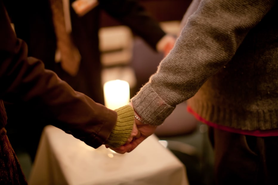 people holding hands around a candle